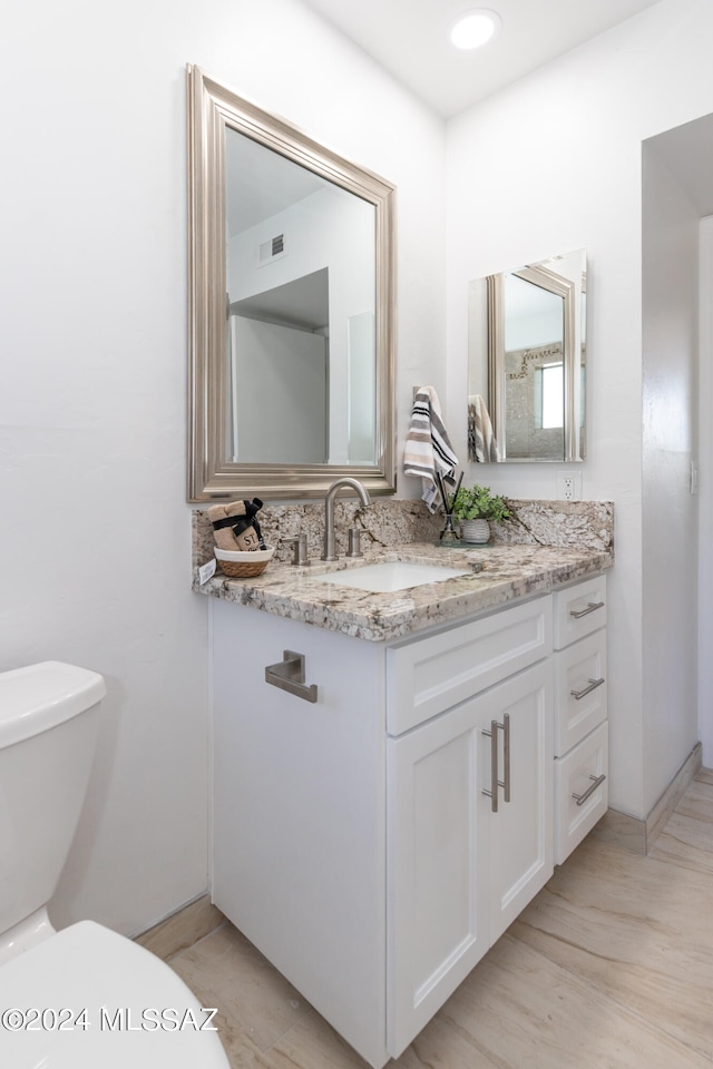 bathroom featuring vanity, hardwood / wood-style flooring, and toilet