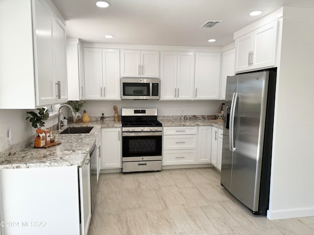 kitchen featuring white cabinets, sink, light stone countertops, and stainless steel appliances