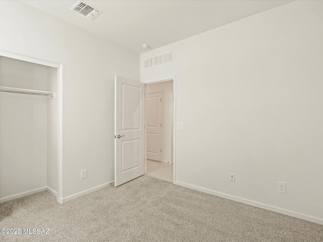 unfurnished bedroom with light carpet and a closet