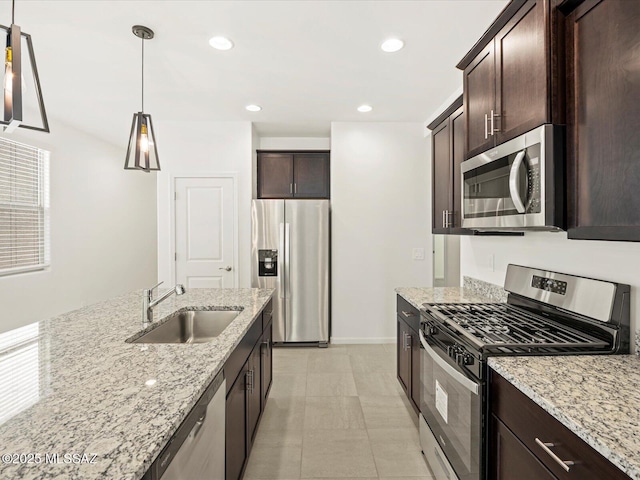 kitchen with sink, appliances with stainless steel finishes, light stone counters, and pendant lighting