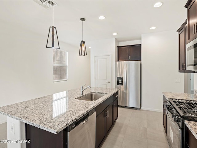 kitchen with a center island with sink, dark brown cabinetry, sink, light stone counters, and appliances with stainless steel finishes