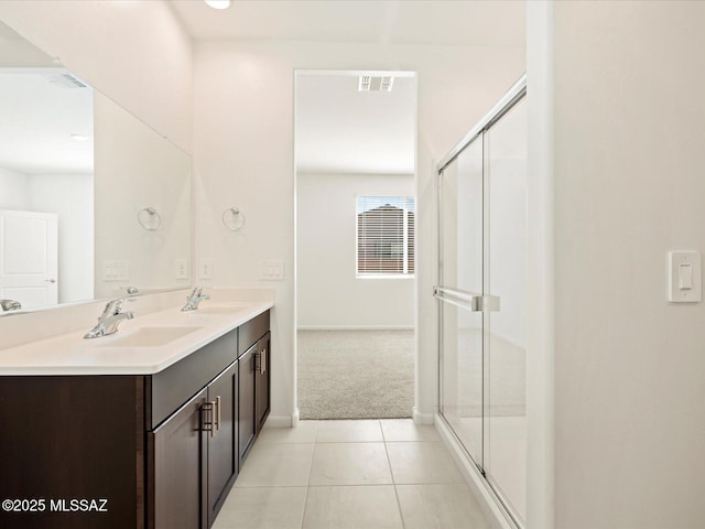 bathroom featuring a shower with shower door, vanity, and tile patterned floors