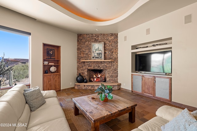 living room with a stone fireplace and built in features