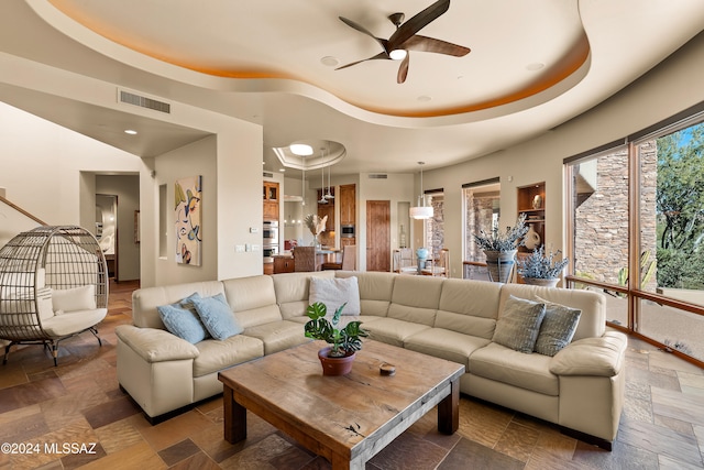 living room featuring ceiling fan and a raised ceiling