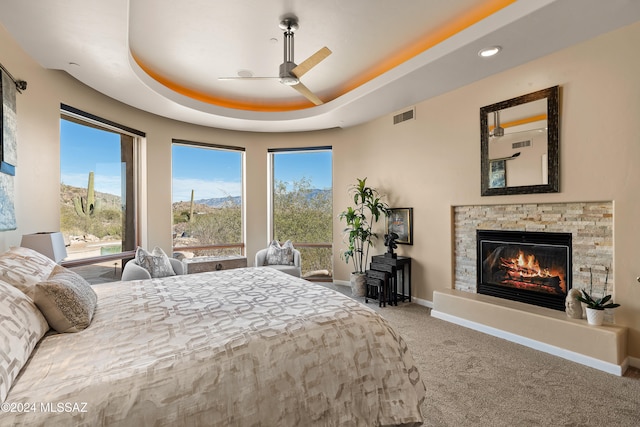 carpeted bedroom with a mountain view, a raised ceiling, and ceiling fan