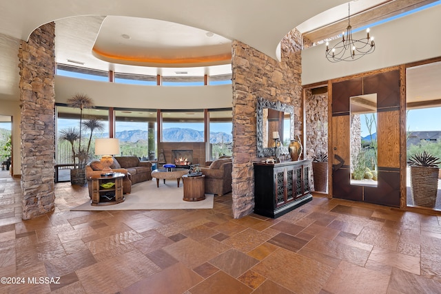 foyer featuring a high ceiling, a raised ceiling, a notable chandelier, a mountain view, and a fireplace