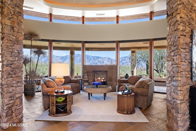 living room featuring a mountain view, plenty of natural light, a towering ceiling, and a tiled fireplace