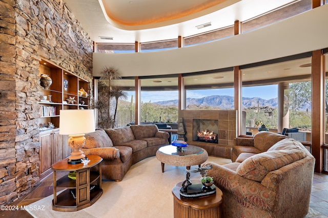 living room with a mountain view, a towering ceiling, a raised ceiling, and a tiled fireplace