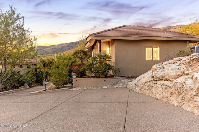 property exterior at dusk with a mountain view and a patio