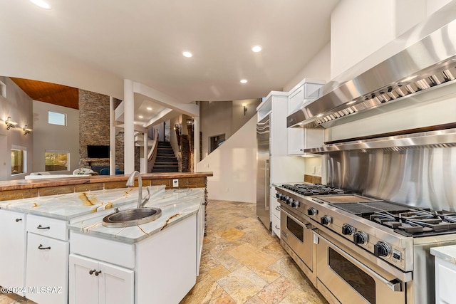 kitchen featuring white cabinets, double oven range, wall chimney exhaust hood, and sink