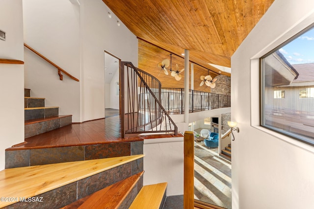 staircase with high vaulted ceiling, wooden ceiling, and hardwood / wood-style flooring