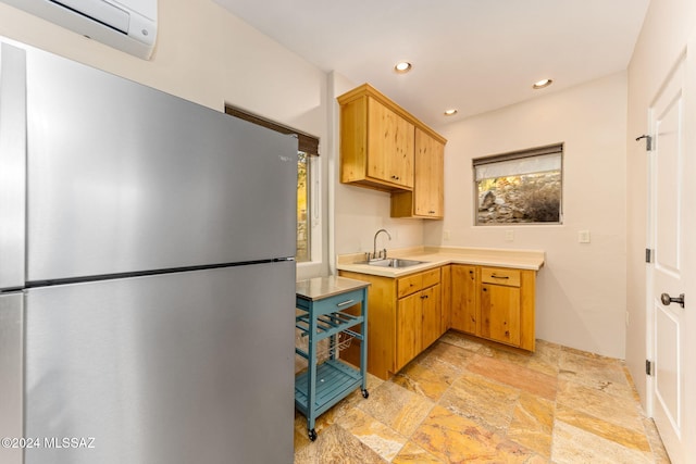 kitchen featuring a wall unit AC, stainless steel refrigerator, a wealth of natural light, and sink