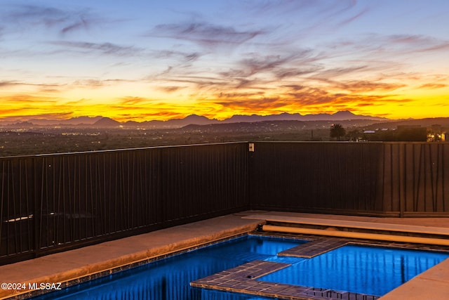 pool at dusk featuring a mountain view