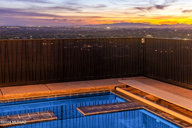 pool at dusk featuring a mountain view and a hot tub