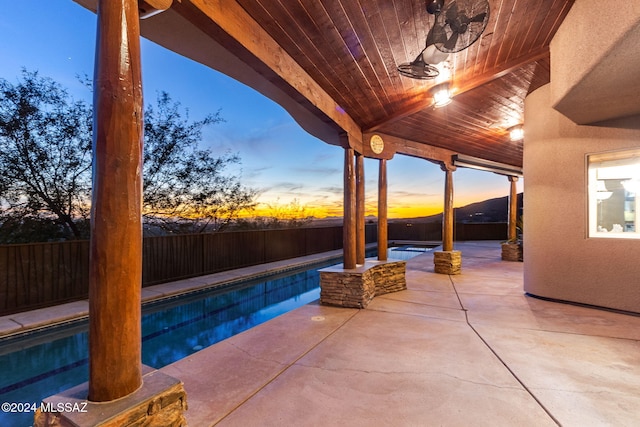 patio terrace at dusk with a swimming pool with hot tub