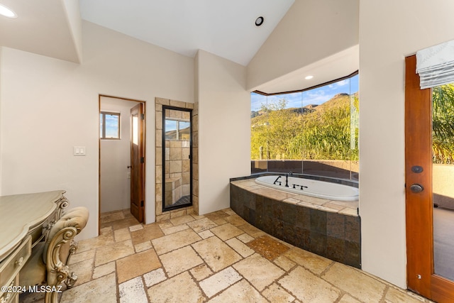 bathroom with a relaxing tiled tub, vaulted ceiling, and a wealth of natural light