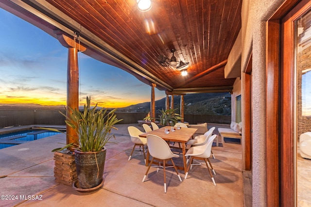 patio terrace at dusk featuring a mountain view and a fenced in pool