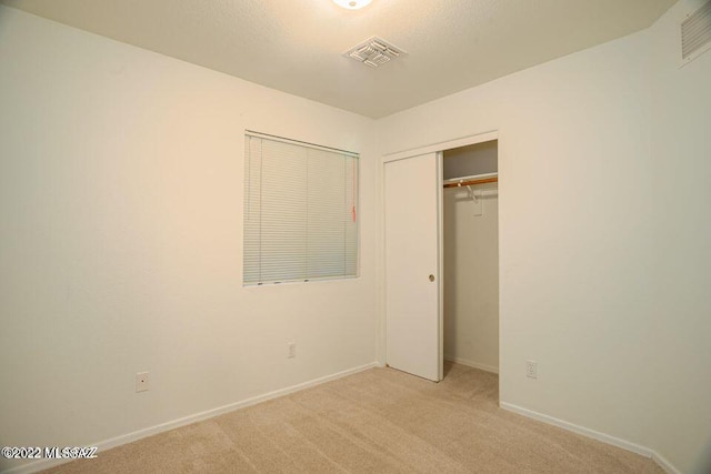 unfurnished bedroom featuring light carpet and a closet