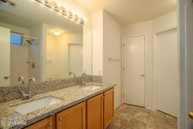 bathroom with tiled shower, vanity, and toilet