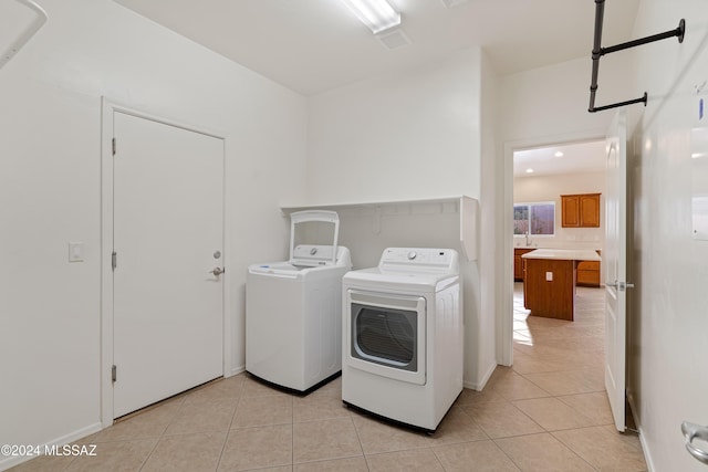 washroom with light tile patterned floors, laundry area, and washer and dryer