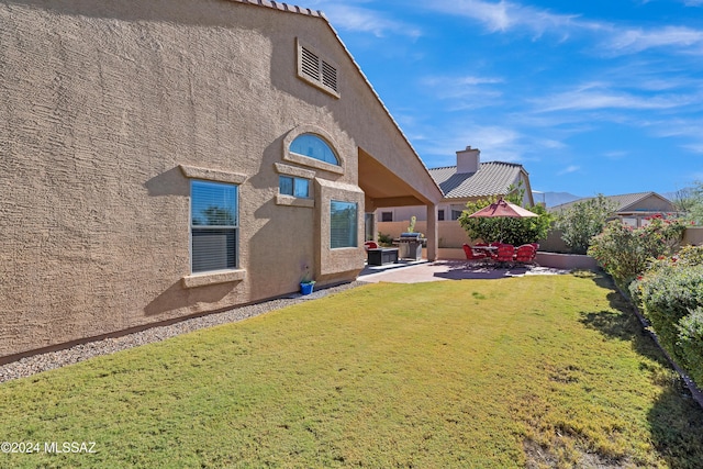 back of property featuring stucco siding, a yard, and a patio area