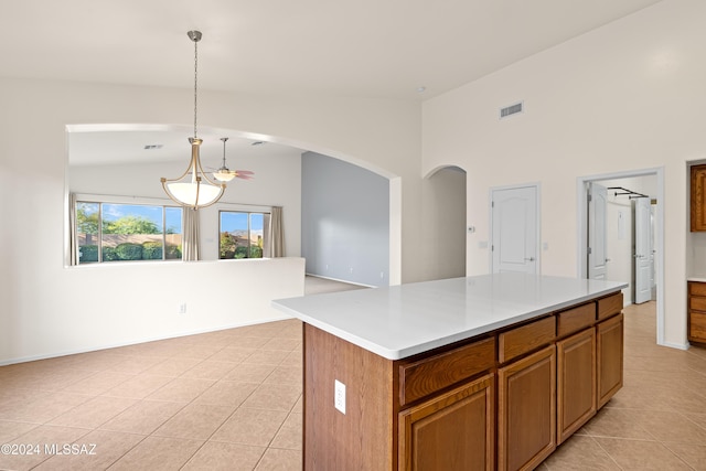 kitchen with light tile patterned floors, brown cabinetry, visible vents, a kitchen island, and light countertops