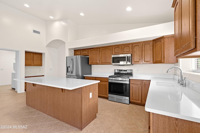 kitchen featuring light tile patterned floors, brown cabinets, stainless steel appliances, and a sink