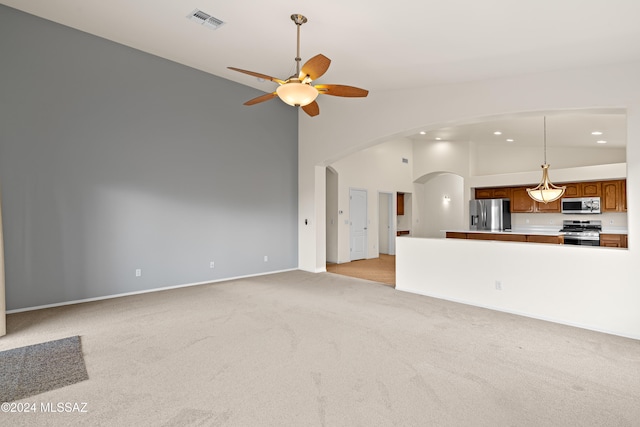 unfurnished living room featuring visible vents, light carpet, arched walkways, high vaulted ceiling, and a ceiling fan