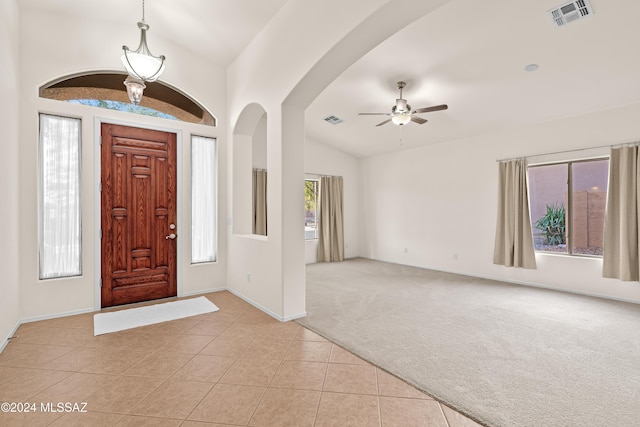 foyer featuring light tile patterned floors, visible vents, light colored carpet, and lofted ceiling