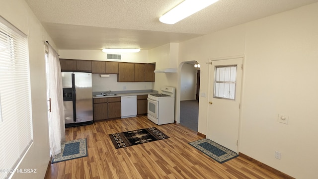 kitchen with dark brown cabinets, white appliances, light hardwood / wood-style floors, and sink