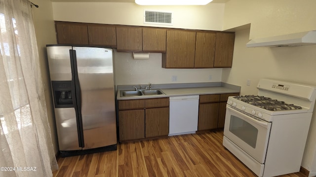 kitchen featuring white appliances, sink, exhaust hood, and dark wood-type flooring