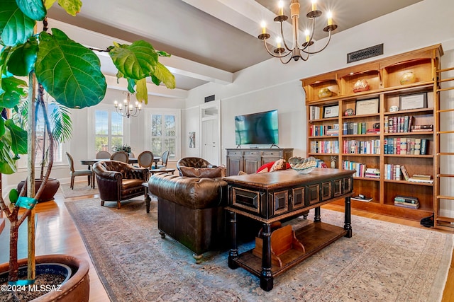 living area featuring hardwood / wood-style floors, beamed ceiling, and a chandelier