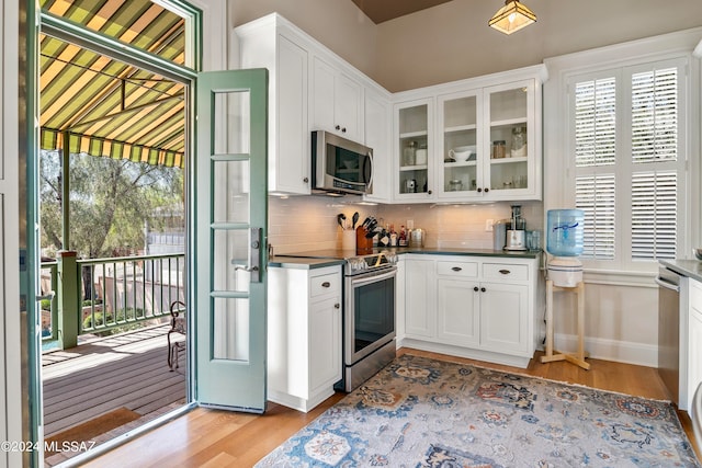 kitchen featuring white cabinets, light wood-type flooring, appliances with stainless steel finishes, and tasteful backsplash