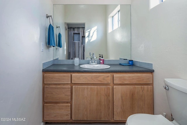 bathroom with plenty of natural light, toilet, and vanity