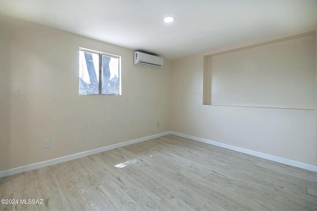 empty room featuring a wall unit AC and light wood-type flooring