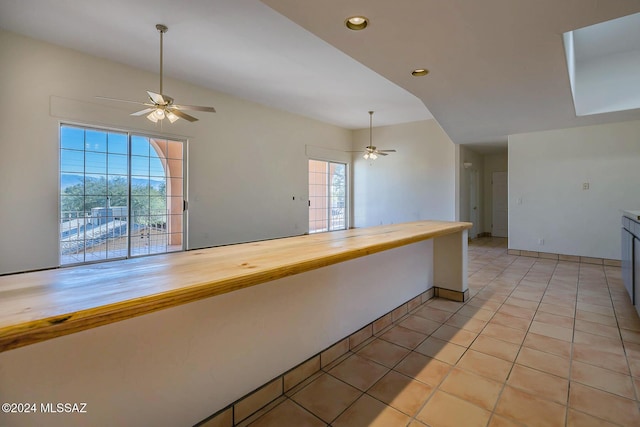 kitchen with wood counters, light tile patterned floors, vaulted ceiling, and ceiling fan