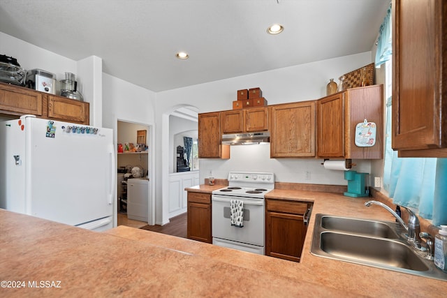 kitchen featuring hardwood / wood-style floors, white appliances, washer / clothes dryer, and sink