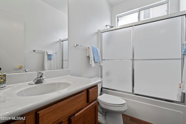 full bathroom featuring hardwood / wood-style floors, vanity, toilet, and bath / shower combo with glass door