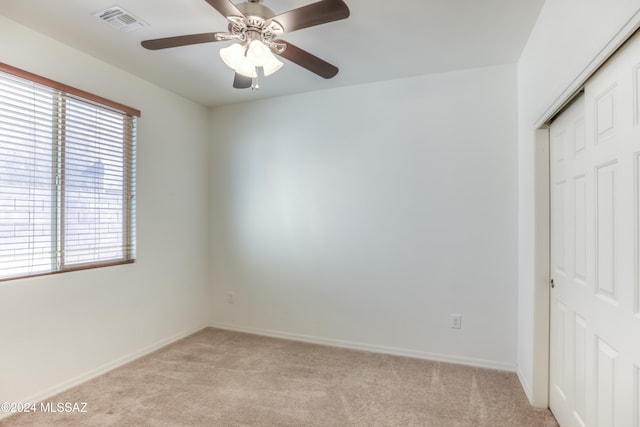 unfurnished bedroom featuring ceiling fan, light colored carpet, and a closet