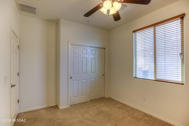 unfurnished bedroom with ceiling fan, light carpet, and a closet