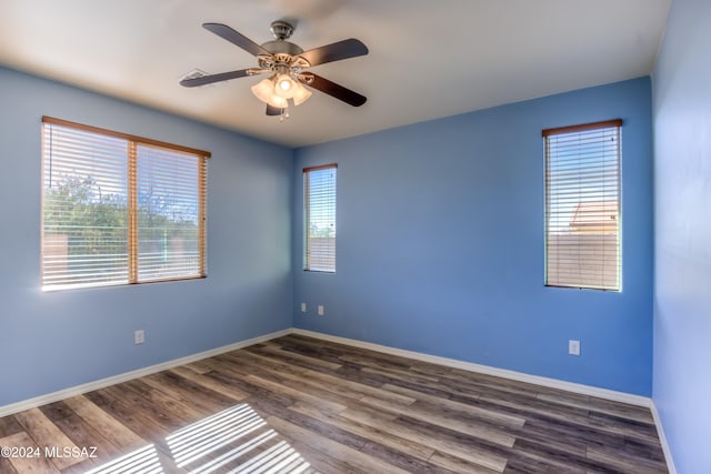 unfurnished room featuring plenty of natural light, ceiling fan, and dark hardwood / wood-style flooring