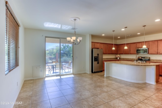 kitchen with stainless steel appliances, light stone counters, a notable chandelier, an island with sink, and light tile patterned floors