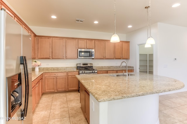 kitchen featuring sink, hanging light fixtures, an island with sink, light tile patterned flooring, and appliances with stainless steel finishes