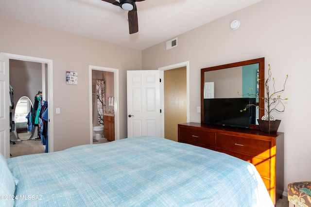 carpeted bedroom with ceiling fan, ensuite bathroom, a closet, and a spacious closet