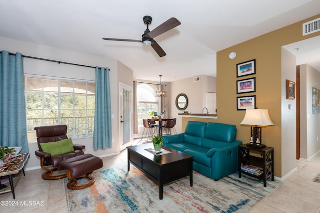 living room with ceiling fan with notable chandelier and light tile patterned floors