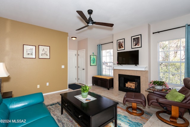 tiled living room with a tiled fireplace and ceiling fan