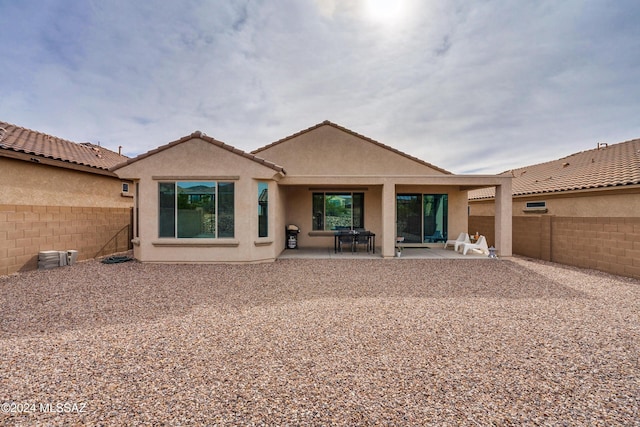back of property featuring a fenced backyard, a tiled roof, stucco siding, and a patio