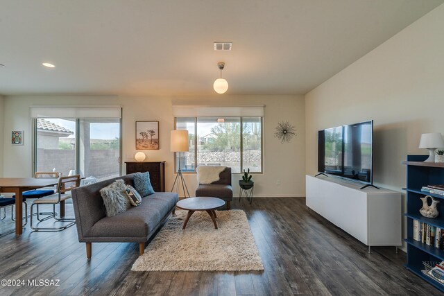 living room featuring visible vents, dark wood-type flooring, baseboards, and a wealth of natural light