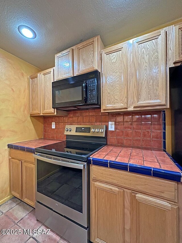 8034 E Shadow Ln, Tucson, AZ 85750 - kitchen featuring stainless steel electric stove, black microwave, tile countertops, a textured ceiling, and decorative backsplash