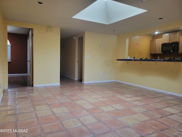 tiled empty room featuring a skylight